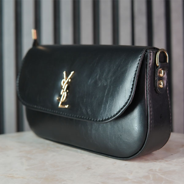 کیف زنانه YSL مشکی با طراحی مینیمال و لوگوی فلزی طلایی، نمای سهرخ روی پسزمینه استودیویی خاکستری