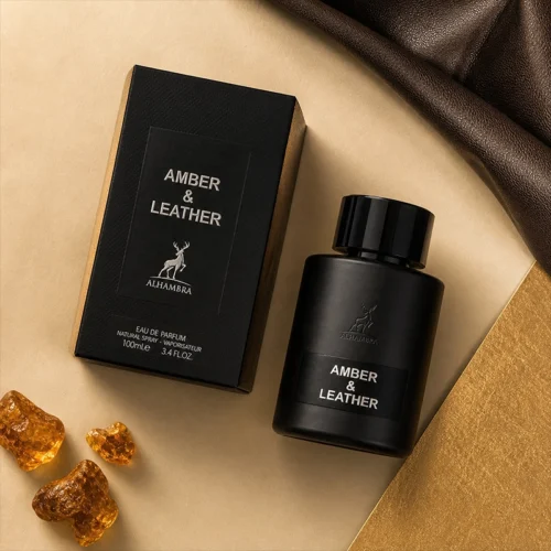 نمای نزدیک عطر آمبر اند لدر الحمبرا با بطری مشکی مات و حکاکی آهو، روی پارچه چرمی مشکی و در کنار تکه‌ای درشت از صمغ کهربا.