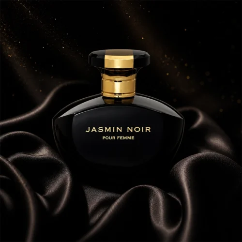 بطری مشکی طلایی عطر Jasmin Noir Pour Femme روی پارچه ابریشمی مشکی