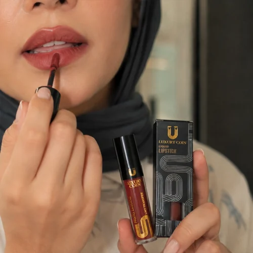 جزئیات بسته‌بندی مشکی و طلایی رژ لب مایع Luxury Coin در دستان مدل.